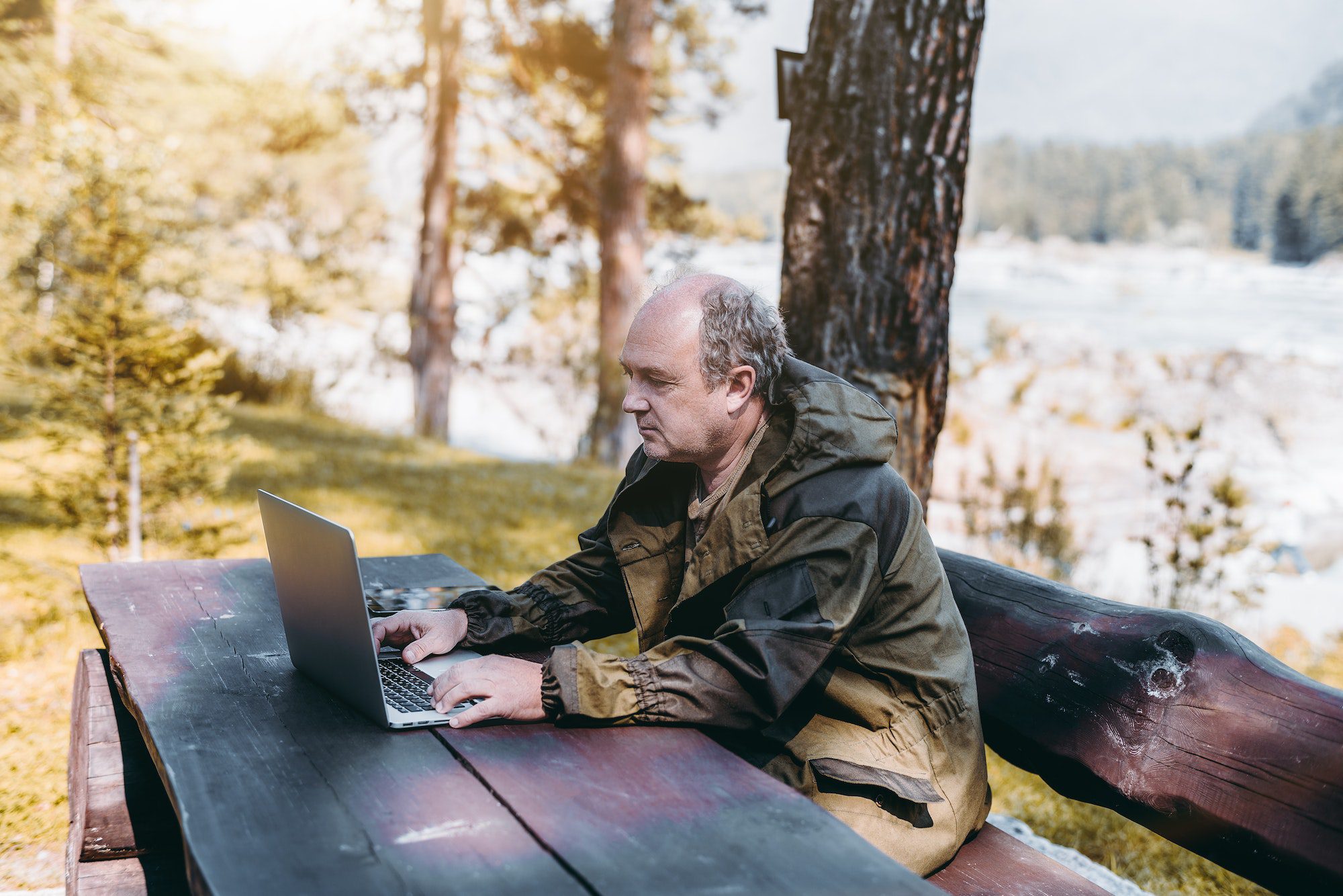 Homme d'affaires avec un ordinateur portable pendant ses vacances en forêt pour découvrir toutes les parties de Medicare.
