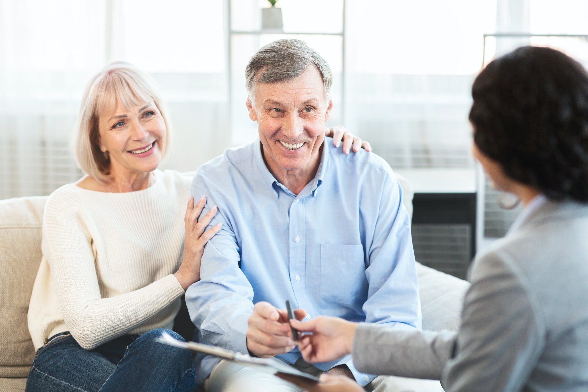 Happy mature couple talking to insurance agent at home about Medicare Part B