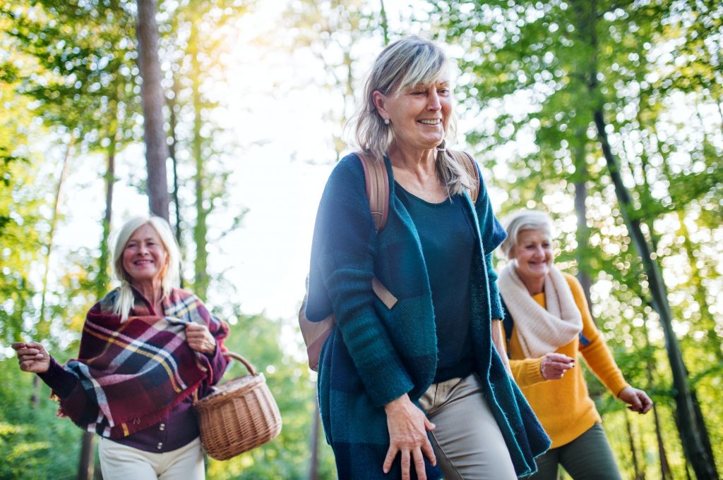 Senior women friends walking outdoors in forest avoiding Medicare Penalties
