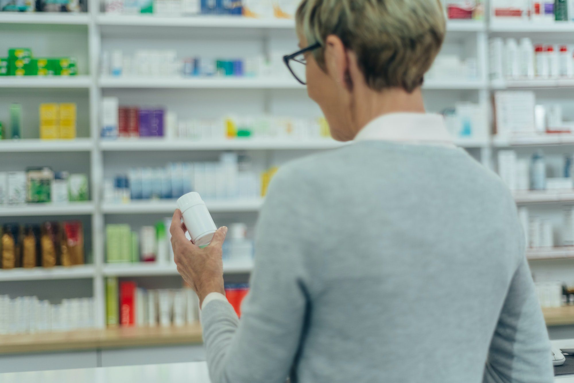 Senior female patient in a pharmacy holding medicament in a hand with Medicare Part D