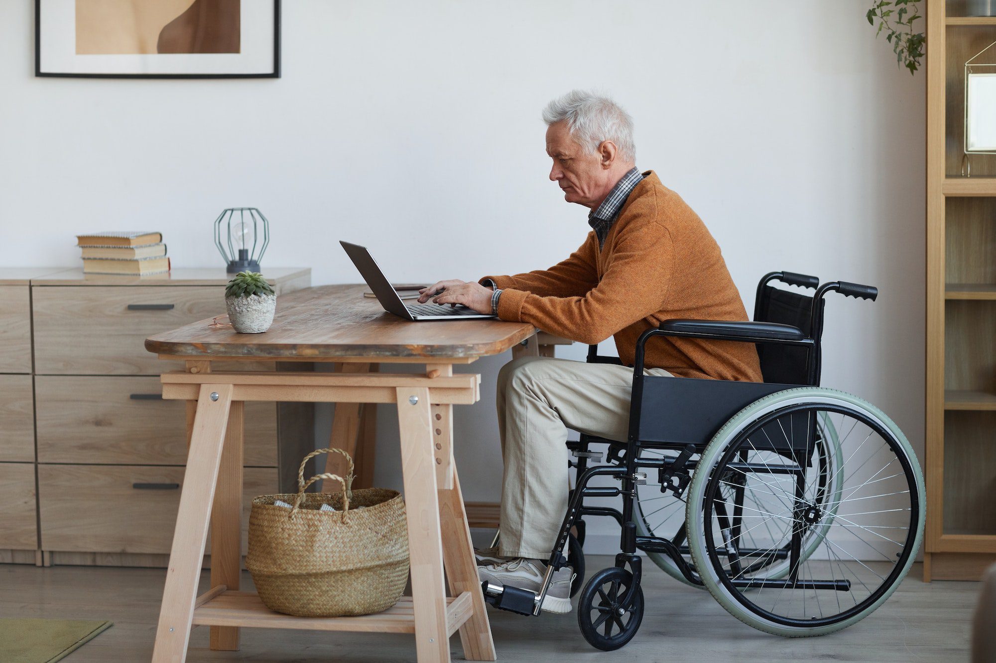 Homme âgé handicapé utilisant un ordinateur au bureau avec un plan pour besoins spéciaux chroniques